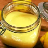 En burk med krämig, solgul lemon curd omgiven av färska citroner. Perfekt för bakning eller som tillbehör.