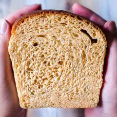 En skiva gyllene sirapslimpa, perfekt för ett gott sirapslimpa recept. Hålls varsamt i händerna.