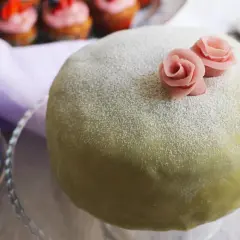 En grön prinsesstårta med rosa rosor, pudrad med florsocker. Perfekt för att fråga hur länge håller prinsesstårta i kylen.