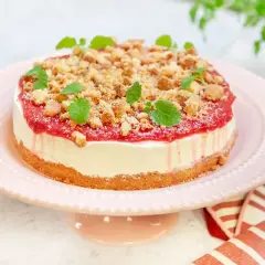 En läcker vit choklad cheesecake med hallon och smulor, dekorerad med mynta. Perfekt för fikat!