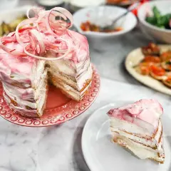 En vacker rabarberkompott tårta med rosa frosting och en skiva upplagd. Perfekt för en somrig fika.