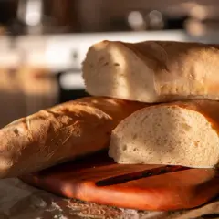 Tre nybakade pain riche, gyllene och inbjudande, ligger staplade på en träskärbräda.