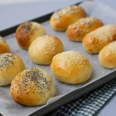 Nybakade bakpulver frallor med vallmofrön och sesamfrön på en plåt. Perfekta för frukost eller fika.