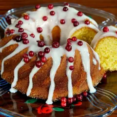 En saftig sockerkaka med sirap istället för socker, dekorerad med vit glasyr och färska lingon. En bit är uppskuren.
