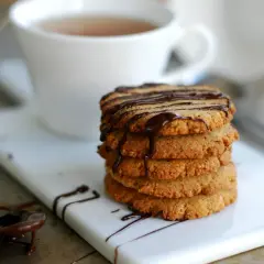 En hög med honungsdränkta kakor, perfekt för att baka med honung istället för socker. En kopp te i bakgrunden.