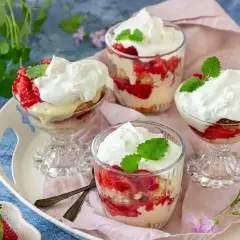 Ljuvlig jordgubbstårta i glas, lager av sockerkaka, färska jordgubbar och vispgrädde. Perfekt sommardessert.