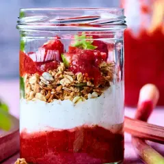 En glasburk med lager av rabarberkompott, yoghurt och granola. Rabarber är giftiga efter midsommar, men denna dessert är säker att njuta av.