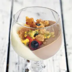 En läcker pannacotta med vit choklad, toppad med bär och smulor.