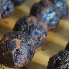 Mörka, chokladiga nutella bollar, pudrade med kakao, ligger uppradade på en träyta. En härlig syn för alla chokladälskare!
