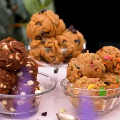 Tre skålar med olika sorters cookie dough recept: choklad med vita chokladknappar, klassisk med chokladknappar och en med färgglada godisbitar.