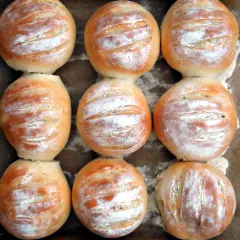 Nio nybakade vetekakor, pudrade med mjöl, redo att avnjutas. Ett perfekt vetekaka recept för hembakat bröd.
