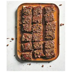 Chokladiga bitar av zserbó recept på en orange bricka, toppade med chokladglasyr och krossad choklad.