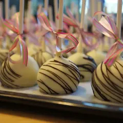 Vita cake pops med chokladmönster och rosa/gröna band. Perfekta för ett festligt tillfälle, som ett enkelt recept på oreo-bakverk.