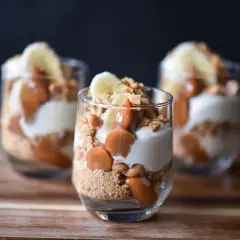 Tre glas med banoffee paj i lager av kexsmulor, krämig fyllning, banan och kolasås.