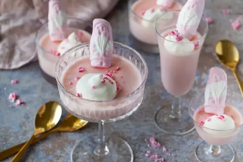 Rosa pannacotta med vispgrädde och skumtomtar, en söt och festlig dessert.