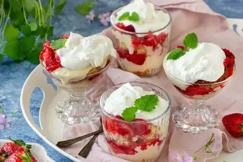 Ljuvlig jordgubbstårta i glas, lager av sockerkaka, färska jordgubbar och vispgrädde. Perfekt sommardessert.