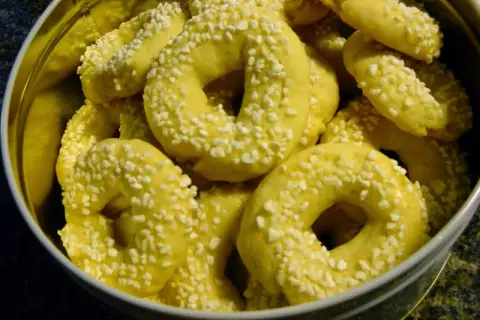 En burk fylld med gyllene kringlor med bakpulver, strösslade med små vita bitar.