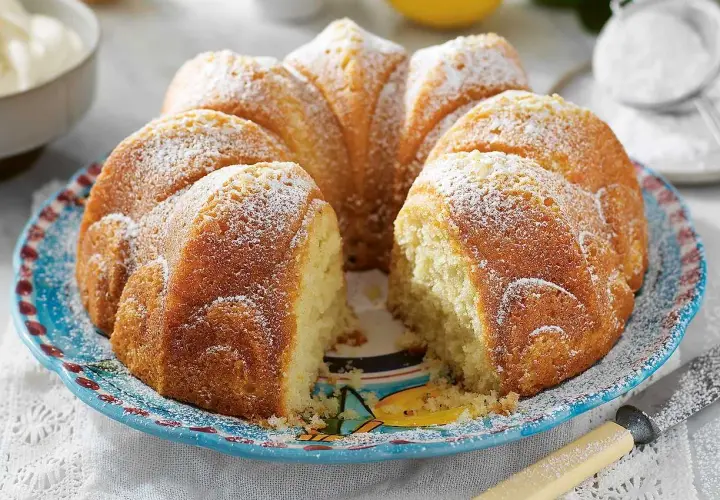 En saftig sockerkaka, perfekt att baka med grekisk yoghurt. Pudrad med florsocker och serverad på en vacker blå tallrik.