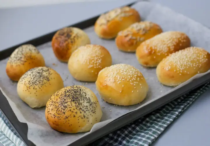 Nybakade bakpulver frallor med vallmofrön och sesamfrön på en plåt. Perfekta för frukost eller fika.