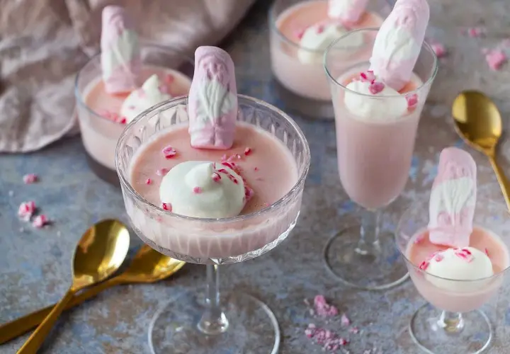Rosa pannacotta med vispgrädde och skumtomtar, en söt och festlig dessert.