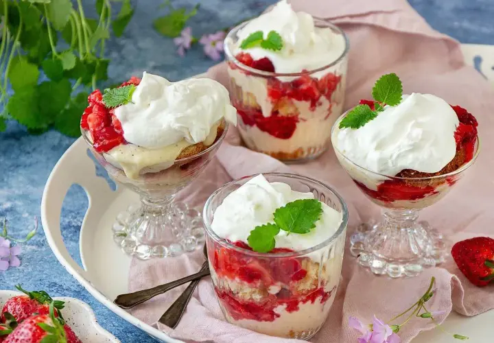 Ljuvlig jordgubbstårta i glas, lager av sockerkaka, färska jordgubbar och vispgrädde. Perfekt sommardessert.