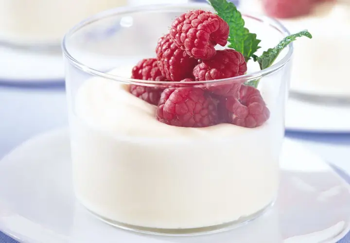 En len vit chokladmousse i glas, toppad med färska hallon och en myntakvist. En perfekt dessert för alla tillfällen.