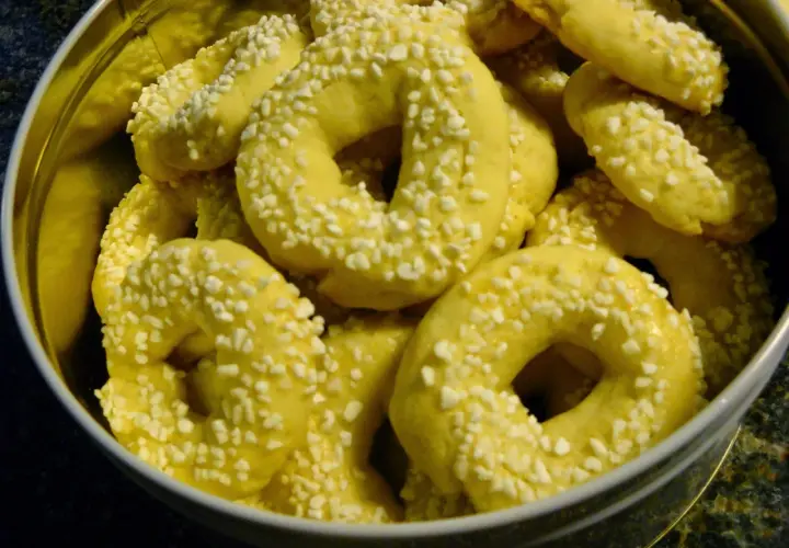 En burk fylld med gyllene kringlor med bakpulver, strösslade med små vita bitar.