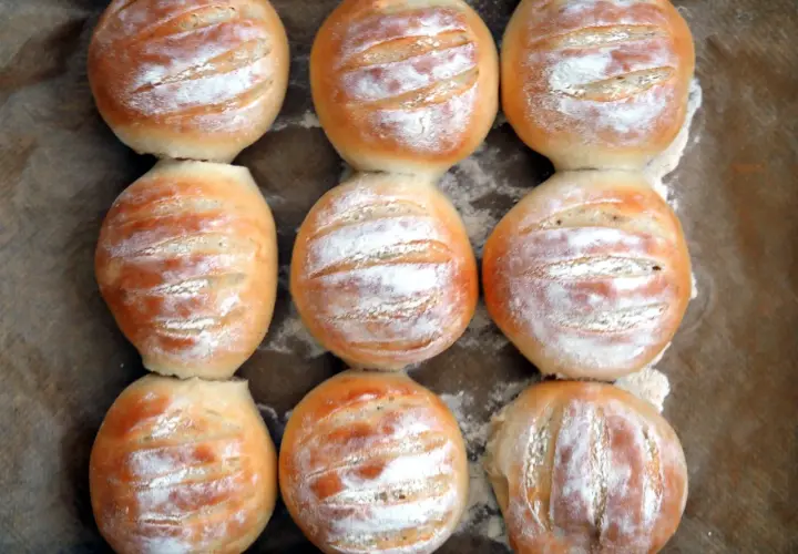 Nio nybakade vetekakor, pudrade med mjöl, redo att avnjutas. Ett perfekt vetekaka recept för hembakat bröd.