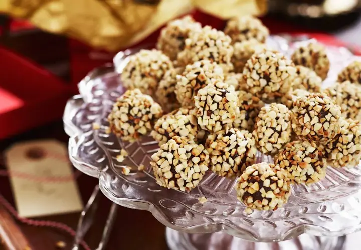En hög med chokladtryffel täckta av hackade nötter på ett glasfat. Perfekt för fikat eller som en gåva.