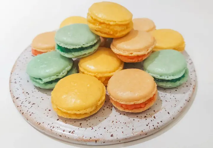 En hög med färgglada macarons i gult, grönt och orange. Perfekt för att fråga: kan man frysa macarons?