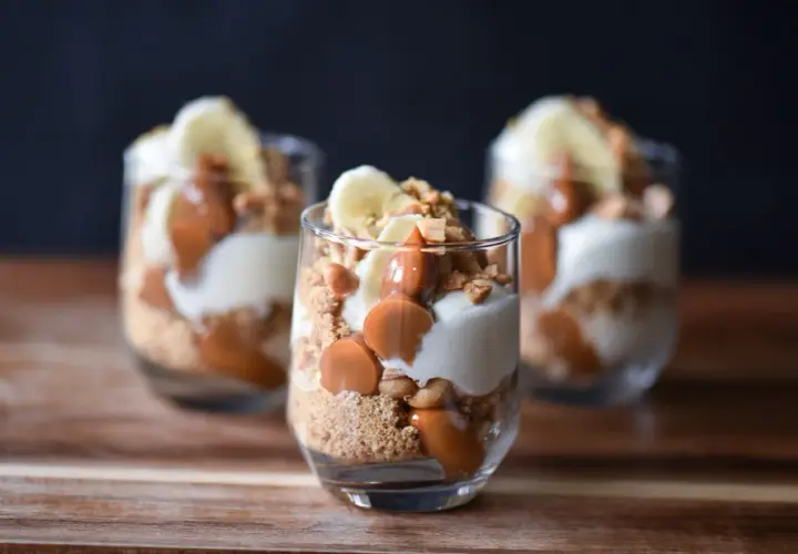 Tre glas med banoffee paj i lager av kexsmulor, krämig fyllning, banan och kolasås.