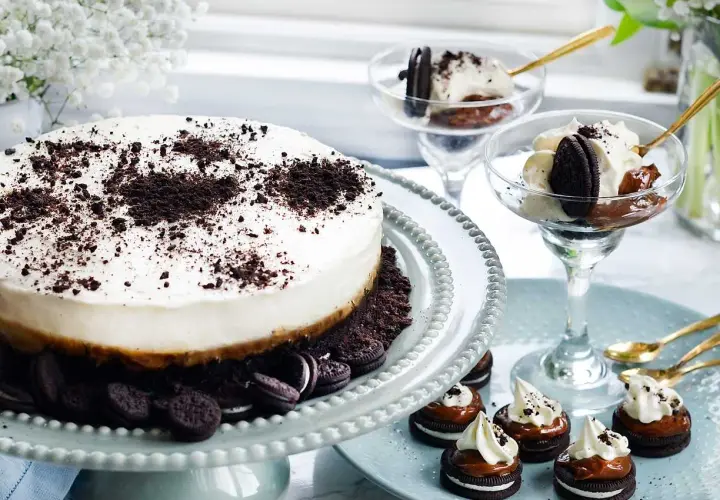 En krämig oreo cheesecake med krossade oreos på toppen. Serveras med små oreo-desserter och i glas.