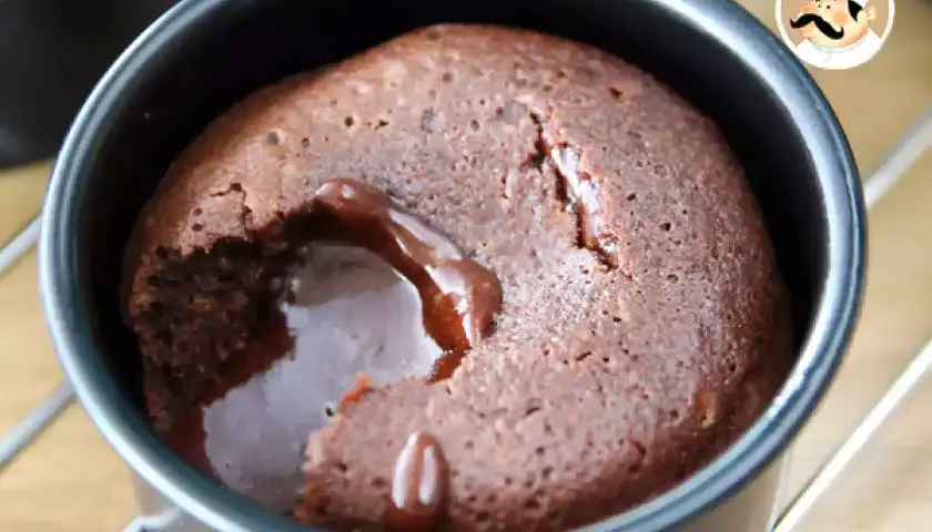 En chokladfondant med rinnande kärna i en svart form. En härlig dessert som smälter i munnen.