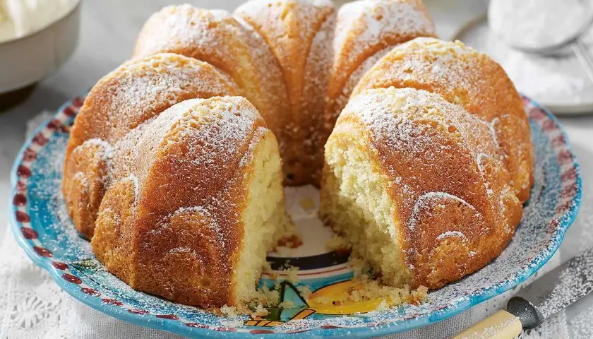En saftig sockerkaka, perfekt att baka med grekisk yoghurt. Pudrad med florsocker och serverad på en vacker blå tallrik.