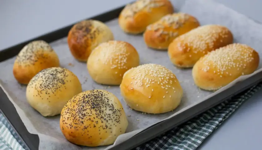 Nybakade bakpulver frallor med vallmofrön och sesamfrön på en plåt. Perfekta för frukost eller fika.