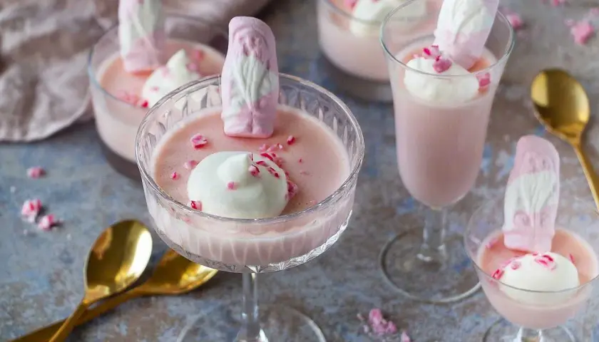 Rosa pannacotta med vispgrädde och skumtomtar, en söt och festlig dessert.