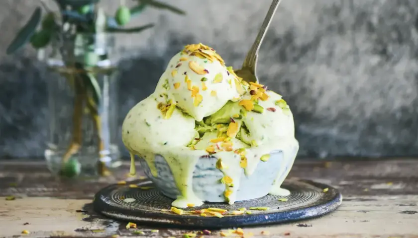 En skål med krämig pistageglass, toppad med hackade nötter. Ett perfekt pistageglass recept för en varm sommardag.