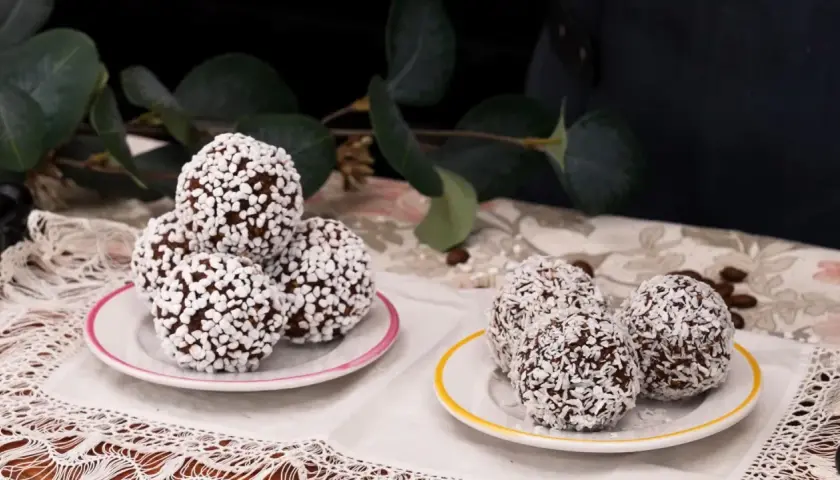 Två fat med chokladbollar, några rullade i kokosflingor och andra i små vita strösselkulor. En härlig syn av kokos bollar!