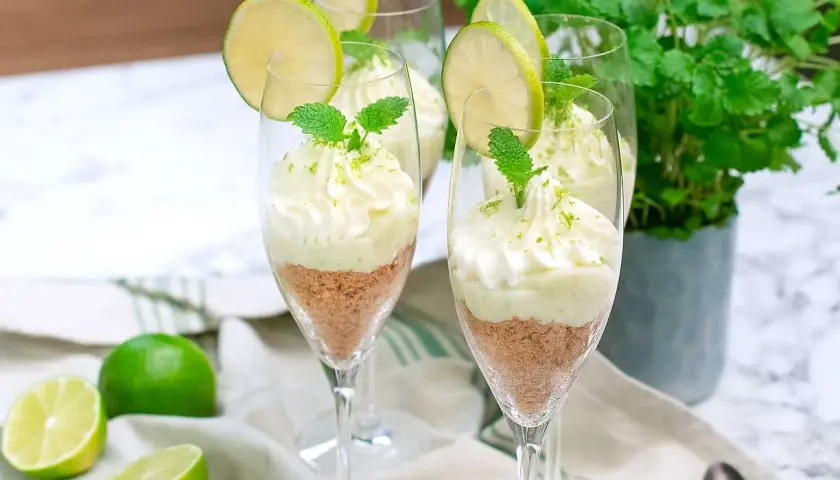 Delikat key lime pie i glas, toppad med vispgrädde och lime. Perfekt för en somrig dessert.