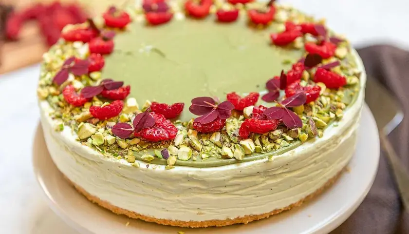 En krämig pistage cheesecake, dekorerad med hallon och pistagenötter. En dröm för alla sötsugna!