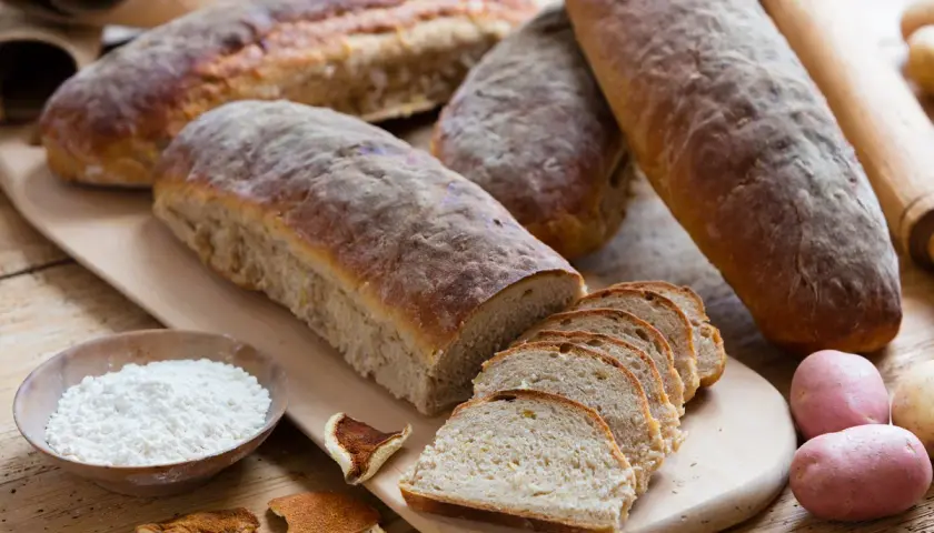 Färskt bröd, potatis och en skål med mjöl, kanske istället för potatismjöl, för en rustik bakning.