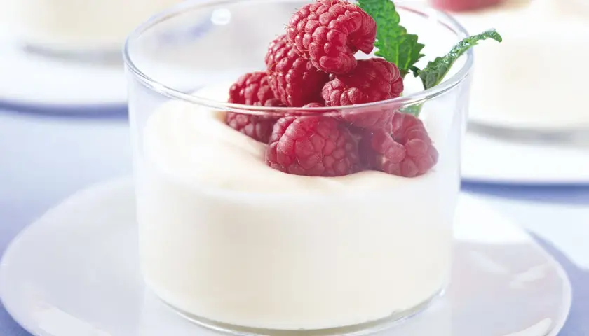 En len vit chokladmousse i glas, toppad med färska hallon och en myntakvist. En perfekt dessert för alla tillfällen.