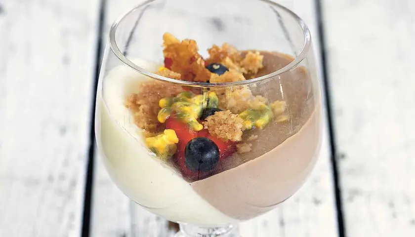 En läcker pannacotta med vit choklad, toppad med bär och smulor.