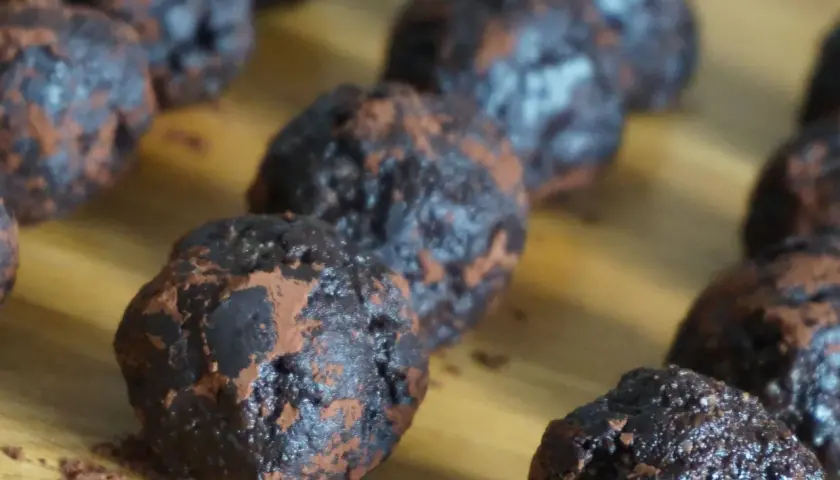 Mörka, chokladiga nutella bollar, pudrade med kakao, ligger uppradade på en träyta. En härlig syn för alla chokladälskare!