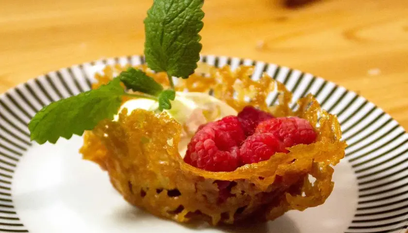 En dessert med glass, hallon och mynta i en krispig knäckflarnskorg. Perfekt till glass!