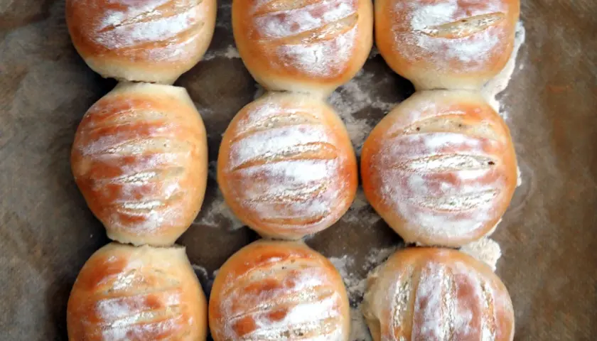 Nio nybakade vetekakor, pudrade med mjöl, redo att avnjutas. Ett perfekt vetekaka recept för hembakat bröd.