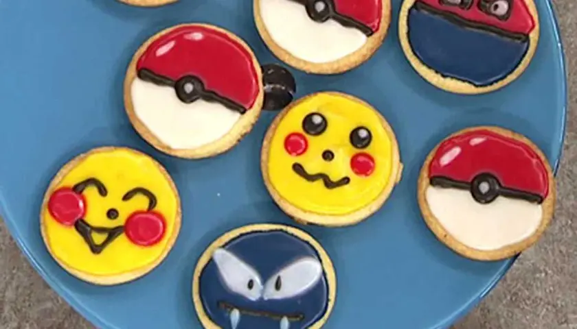 Sju dekorerade kakor på en blå tallrik, inklusive Pikachu, Pokémons och en Gastly. En härlig pokemon tårta för alla fans!