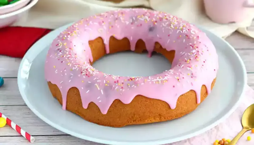 En stor donut tårta med rosa glasyr och strössel. Perfekt för ett kalas!