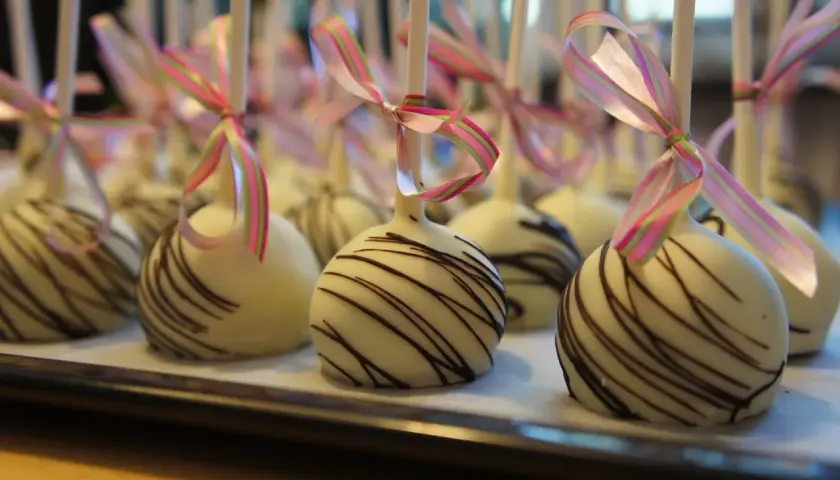 Vita cake pops med chokladmönster och rosa/gröna band. Perfekta för ett festligt tillfälle, som ett enkelt recept på oreo-bakverk.