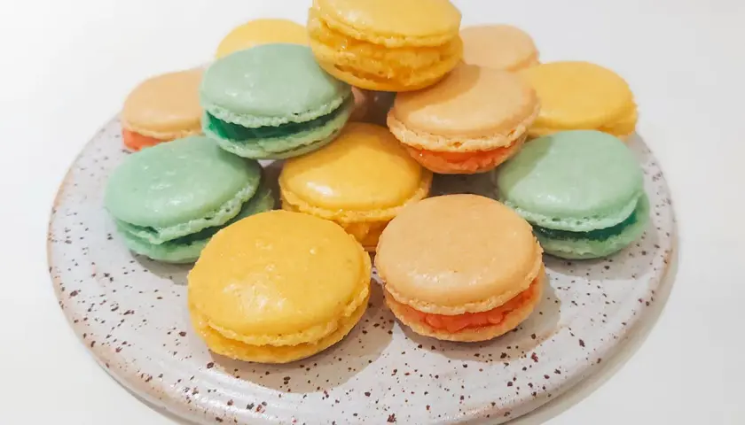 En hög med färgglada macarons i gult, grönt och orange. Perfekt för att fråga: kan man frysa macarons?